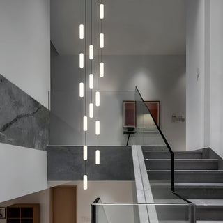Pluvara capsule LED staircase chandelier cascading down a modern marble stairwell with a glass railing