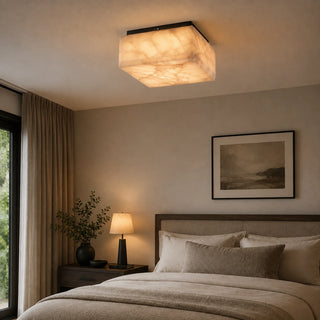 Quadara square alabaster flush mount ceiling light with a black finish glowing warmly above the bed in a modern bedroom