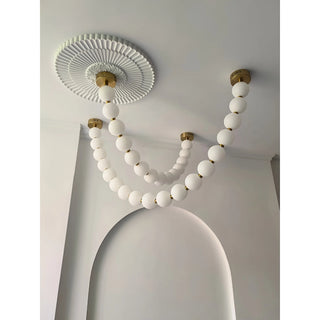 Minimalist white glass pearl chandelier with gold details on decorative ceiling arch