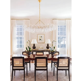 Rectangular glass chandelier with gold finish installed above a modern dining table.