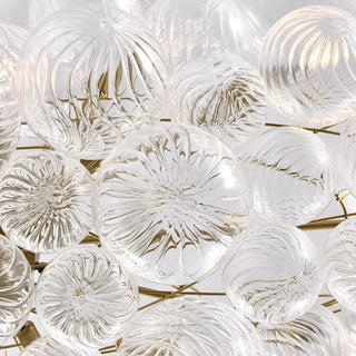 Close-up of clear ribbed glass globes with sculptural swirl texture on rectangular gold chandelier