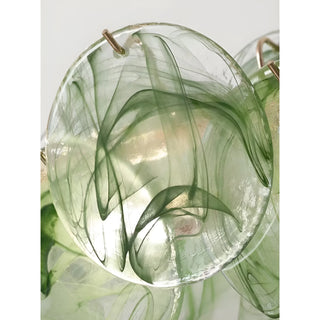 Close-up of sage green textured glass disc with sculptural swirl pattern on modern round chandelier