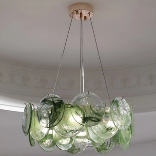 Sage green sculptural glass chandelier installed in modern dining room setting