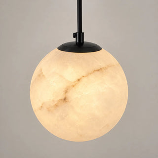 Selenara alabaster globe pendant with a black cord as bedside lighting in a warm bedroom