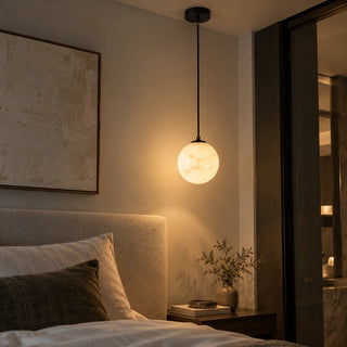 Selenara alabaster globe pendant light with a matte black canopy, lit, on a grey background