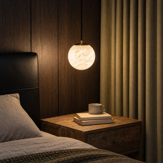 Selenara alabaster globe pendant with a brass canopy glowing warmly in a dark wood bedroom