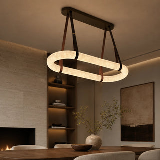 Sellara alabaster oval LED chandelier over a dining table beside a travertine fireplace in a warm modern room