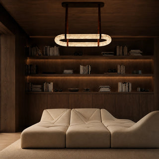 Sellara alabaster oval chandelier suspended over a cream sofa in a dark wood library den