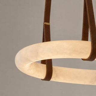 Close-up of a Sellara camel leather strap and brass keeper wrapping the natural alabaster loop