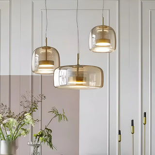 Set of three amber glass pendant lights in Nordic minimalist dining room interior, featuring warm light and gold accents