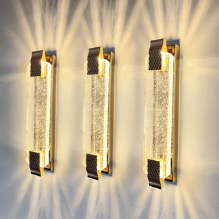 Three crystal wall sconces casting radiant light patterns on a wall