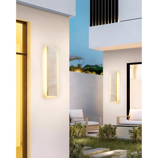 Pair of Solea travertine wall lights softly illuminating a landscaped garden in modern architectural setting