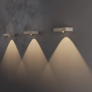 set of three travertine wall lamps creating geometric light patterns on wall