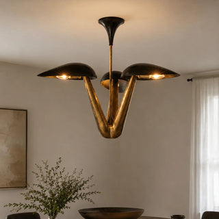 Trombara three-light brass chandelier with black dome shades glowing over a dining table