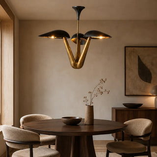 Trombara brass and black dome chandelier suspended above a round wooden table in a warm mid-century dining room