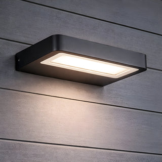 Sleek LED wall light affixed to dark wood siding, emitting ambient downward glow