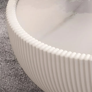 Close-up of ribbed PU leather texture and marble tabletop edge of white round coffee table
