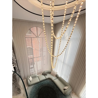 Verona Grand Crystal Staircase Chandelier illuminating a modern double-height living room with cascading light strands