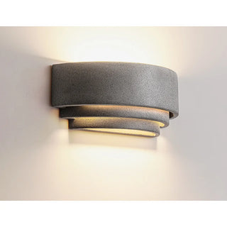 Warm LED glow from textured grey Wabi-Sabi outdoor wall sconce with layered silhouette