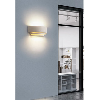 Layered white microcement sconce adding ambiance near large glass facade