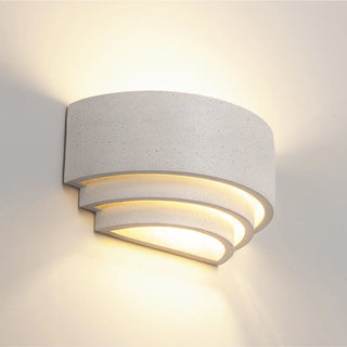 White sandstone wall sconce diffusing warm light in layered minimalist form