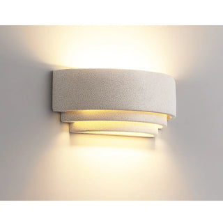 Soft glowing wall light in natural white microcement illuminating with layered design