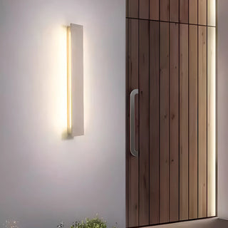 White elongated outdoor wall light illuminating entrance next to a modern wooden front door