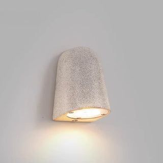 White sandstone microcement wall lamp casting soft light on neutral wall