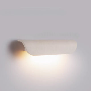 Side view of white concrete wall light mounted on wall, glowing warmly